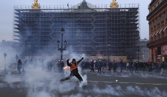 A protester kicks a tear gas canister in front of the Opera at the end of a rally against the pension reform in Paris, France, Thursday, March 23, 2023. French legislators are preparing to vote on a sweeping justice reform bill that would allow law enforcement agents to remotely tap into the camera, microphone, and location details from a suspect&#x27;s phone and other connected devices. (AP Photo/Aurelien Morissard, File)