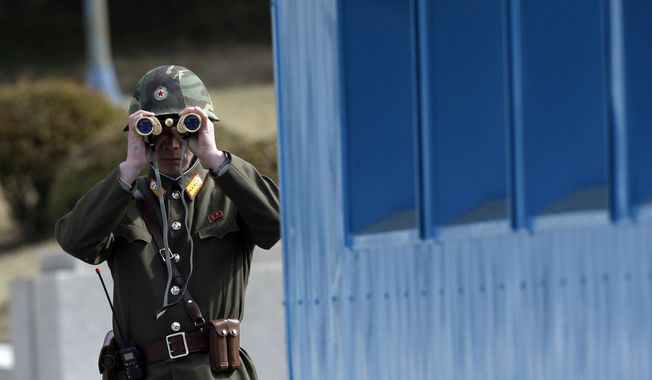 A North Korean soldier looks at the southern side through a pair of binoculars at the border village of Panmunjom, in the Demilitarized Zone, DMZ, that separates the two Koreas since the Korean War, in Paju, north of Seoul, South Korea, Tuesday, March 19, 2013. A series of low-slung buildings and somber soldiers dot the landscape of the DMZ, the swath of land between North and South Korea where a soldier on a tour crossed into North Korea on Tuesday, July 18, 2023, under circumstances that remain unclear. (AP Photo/Lee Jin-man, File)