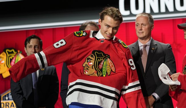 Connor Bedard puts on a Chicago Blackhawks jersey after being picked by the team during the first round of the NHL hockey draft Wednesday, June 28, 2023, in Nashville, Tenn. (AP Photo/George Walker IV)