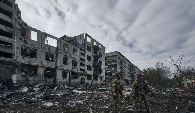 FILE - Ukrainian soldiers pass by houses ruined in the Russian shelling in Bakhmut, Donetsk region, Ukraine, Thursday, Nov. 10, 2022. Despite Russian claims to have captured the Ukrainian city of Bakhmut, top Ukrainian military leaders insist the grinding nine-month battle there is not over. Although Ukraine now controls only a small part of the city, Kyiv says its troops played a key role in the strategy of exhausting Russian forces and will carry on with the fighting. (AP Photo/Libkos, File)