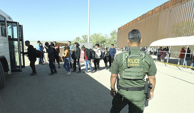 A U.S. Border Patrol agent watches as undocumented immigrants board a bus at a U.S. Border Patrol checkpoint Thursday, May 11, 2023 in Yuma, Ariz. (Randy Hoeft//The Yuma Sun via AP)